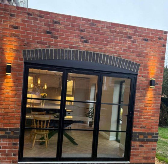 Arched black steel-framed doors set in red brick